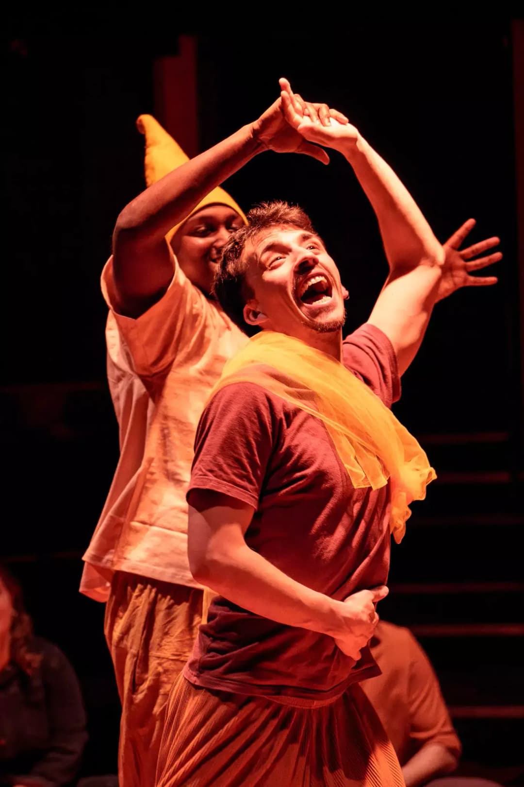 Two actors joyfully reach and smile during a sensory-friendly performance of Twelfth Night by Flute Theatre, engaging autistic participants through Shakespearean play and the Hunter Heartbeat Method.