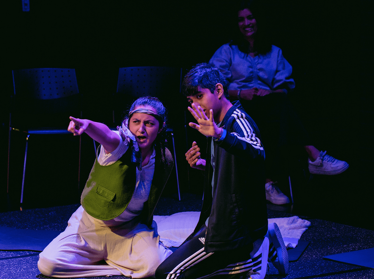 A Flute Theatre actor kneels beside a young autistic participant, pointing into the distance with intense focus. This interactive moment demonstrates how Shakespeare’s stories are adapted through the Hunter Heartbeat Method to build trust and communication.