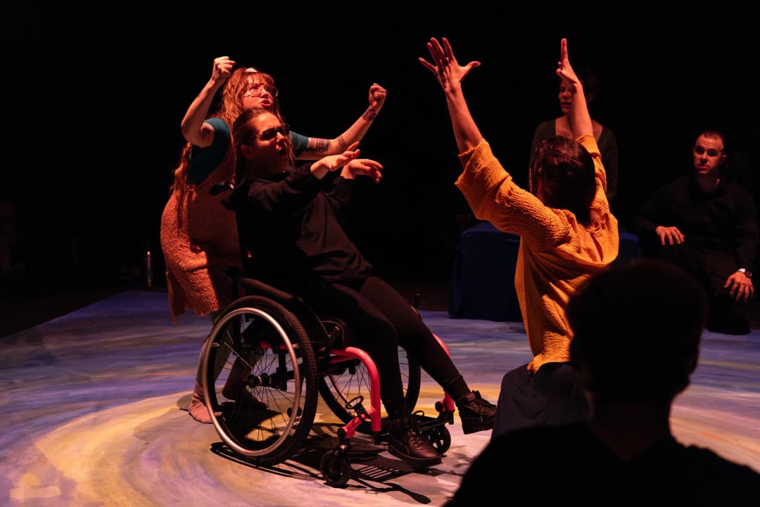 Inclusive performance of Pericles in Denver by Flute Theatre, featuring actors in a wheelchair and others in expressive movement under warm stage lighting.