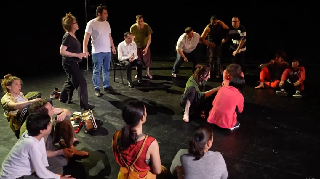 A theatre session with autistic adults and performers interacting on stage, using music and movement to engage the group.