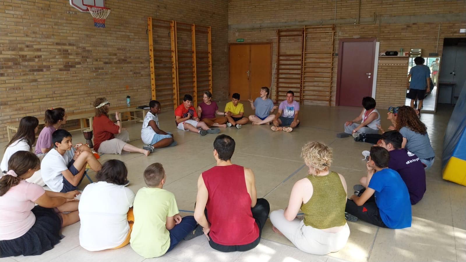 A diverse group of participants from the theatre company sit in a circle on the floor at Centre d’Educació Especial Montserrat Montero in Granollers, Catalunya, during an inclusive workshop in 2025.