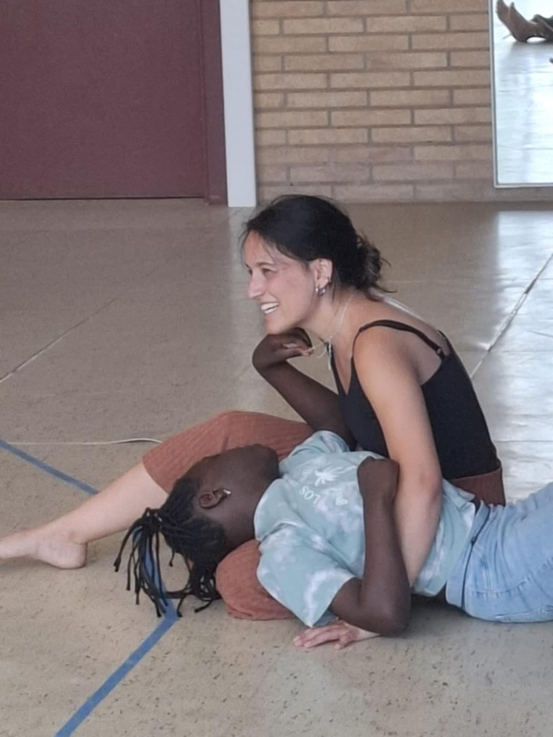 A girl rests comfortably on another person’s lap, both smiling warmly in a relaxed and caring environment at Montserrat Montero Special Education Centre in Granollers.
